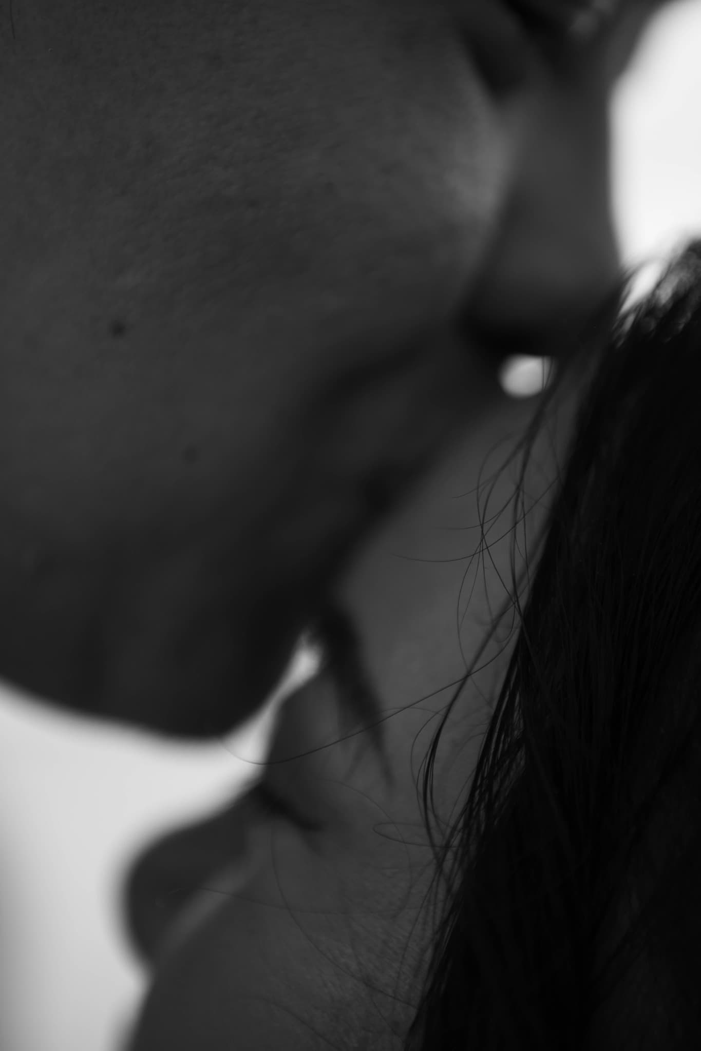 Close-up black and white photograph of two people's faces in a tender and intimate moment.