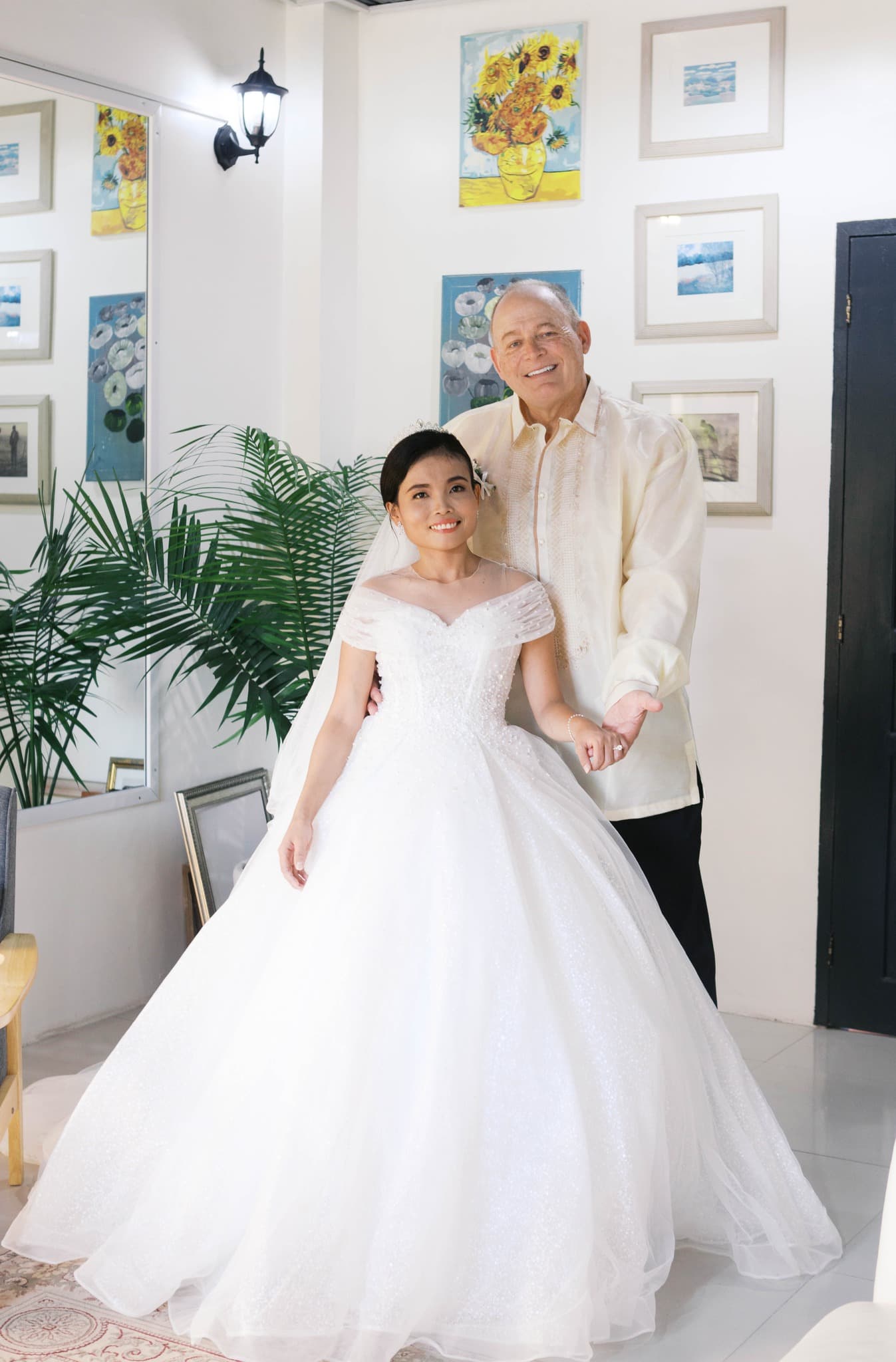 Smiling bride in a white ballgown and groom in a Barong Tagalog pose together.